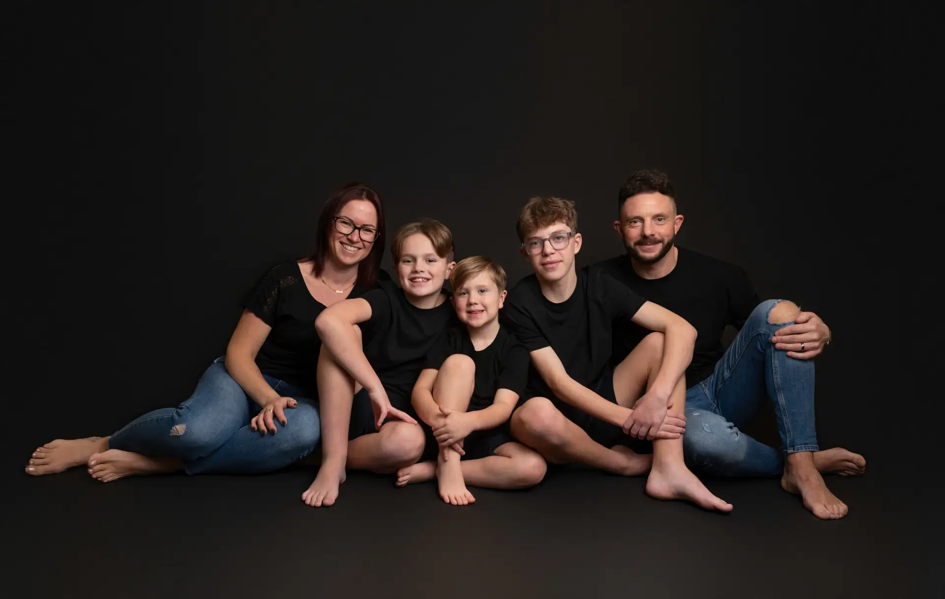 Family portrait with two parents and three children against a black background