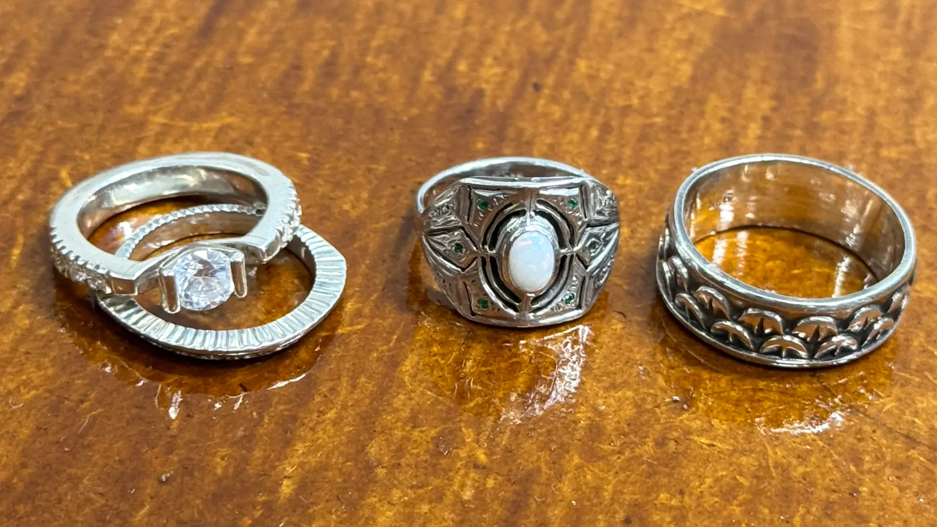 Four bespoke handcrafted rings against a varnished wooden surface