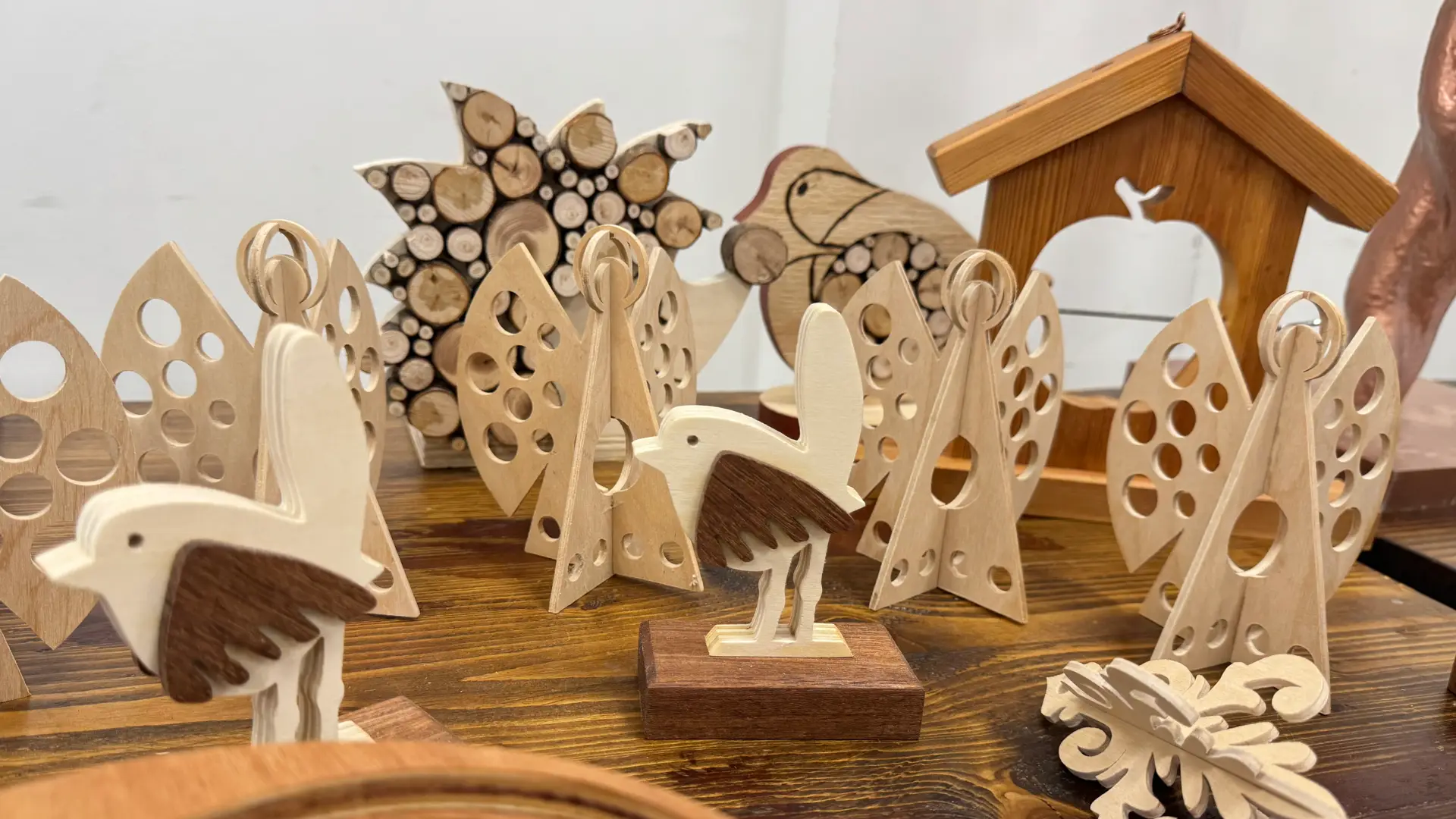 A variety of handcrafted wooden items, including wooden bird ornaments, a birdhouse and an insect hotel