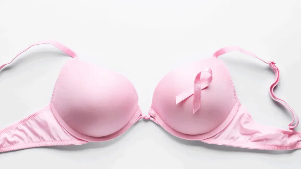 Pink bra laid flat on a white background. A pink breast cancer ribbon embellishes one side of the bra